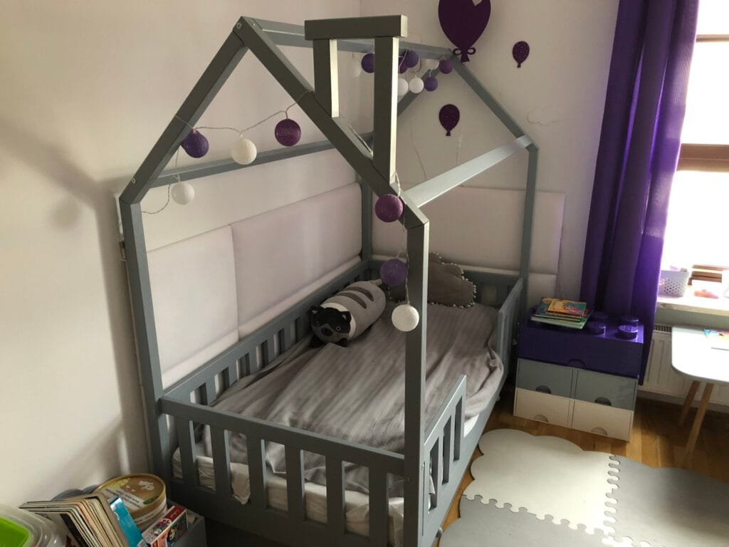 Szare lóżko dla trzylatka z daszkiem i kominkiem.