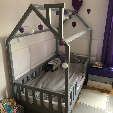 Szare lóżko dla trzylatka z daszkiem i kominkiem.