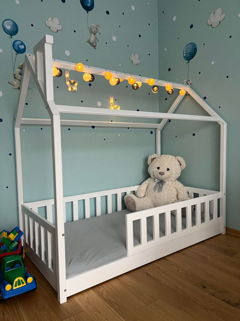 Łóżko domek z barierkami, białe, bez szuflad dla dzieci.