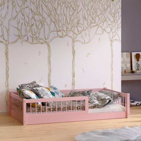 Łóżko dla dziecka pojedyncze, niskie, podłogowe z barierką w kolorze różowym z barierkami.